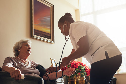 Female doctor measuring blood pressure of old lady