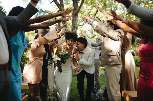 Joyful wedding celebration with the couple and their friends under an archway
