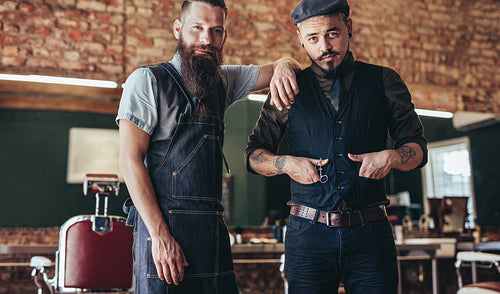 Barber with stylish young man standing at salon