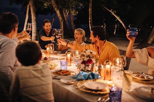 Family toasting with drinks during outdoor dining under palm trees