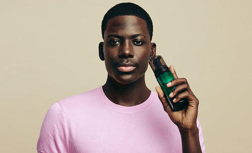 Portrait of a young black man holding a face wash bottle