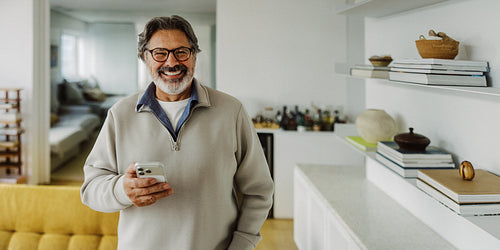 Senior man holds a smartphone at home