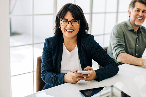 Business woman holding a smart phone in a boardroom