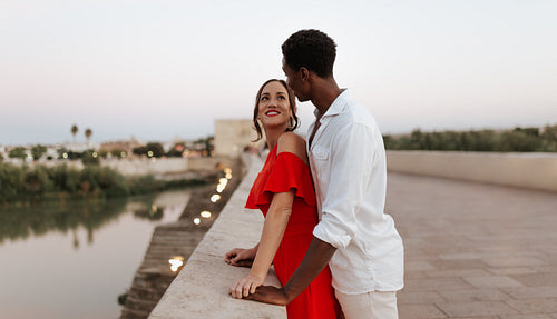Romantic couple standing on a bridge at sunset