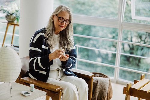 Senior woman tests blood glucose at home