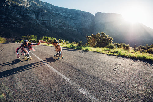 Couple skating down the road on a sunny day