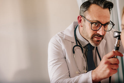 Male doctor examining patient's ear