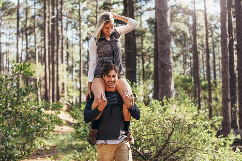 Man carrying his woman partner on his shoulders while trekking in forest