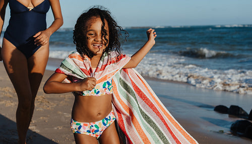 Happy child enjoying a beach vacation wrapped in a striped towel