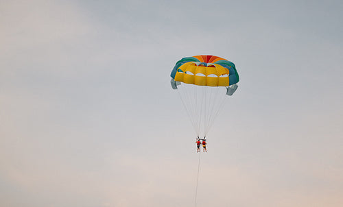 Two people parasailing up high in the sky during a vacation
