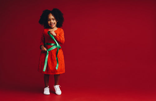 Smiling kid playing with a satin ribbon around her waist