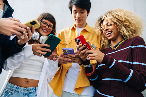 Friends laughing with smartphones in a happy group
