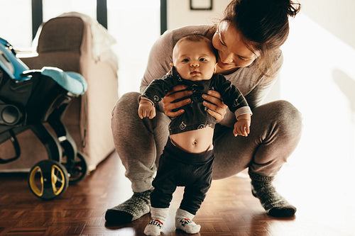 Woman holding her baby squatting on floor