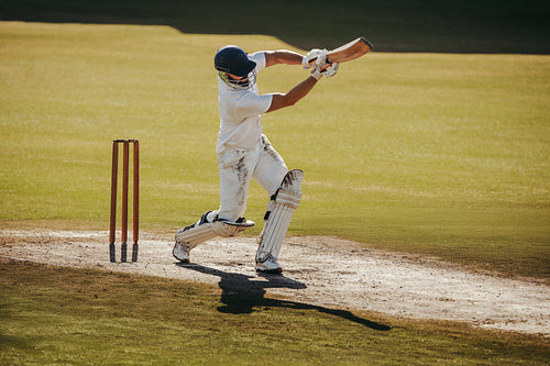 Cricket batsman playing a shot on a professional pitch during a match