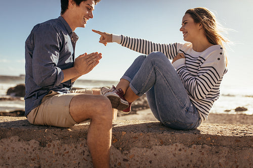 Couple sitting on sea wall having fun