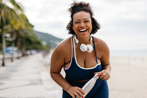 Excited for fitness: Young woman laughing in sportswear on a beach promenade