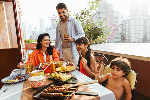 Smiling Latin American family enjoying an outdoor meal together on a sunny day