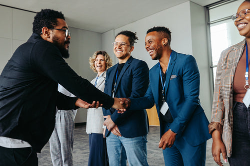 Diverse professionals in a corporate office greeting each other with a handshake