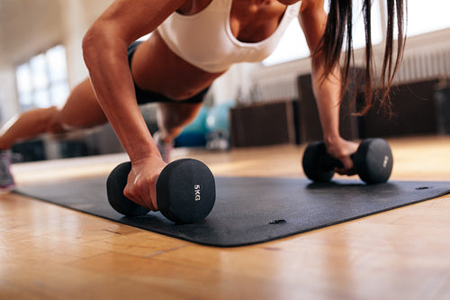 Woman doing pushups on dumbbells