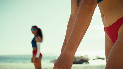 Close-up handheld shot of female beach volleyball players getting ready to play
