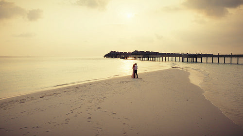 Romantic couple dancing barefoot on tropical beach at sunset