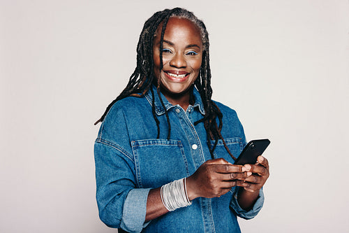 Happy mature woman smiling while holding a smartphone