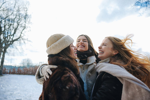 Friends watch women hugging outdoors in winter snow