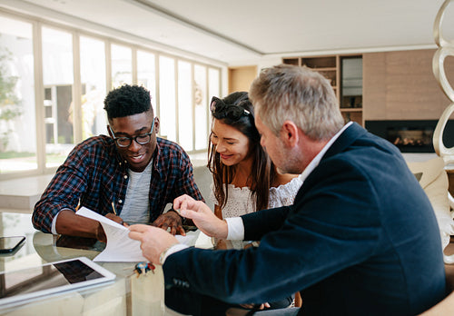 Couple in real estate agency signing property contract documents