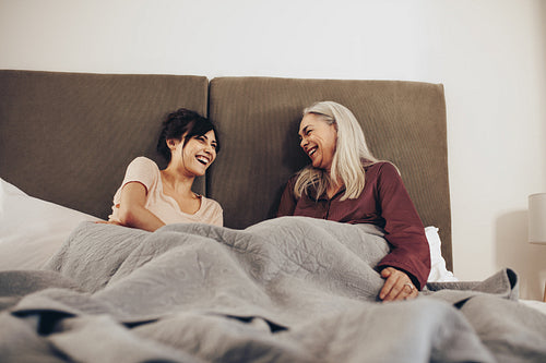 Mother and daughter sitting on bed and talking