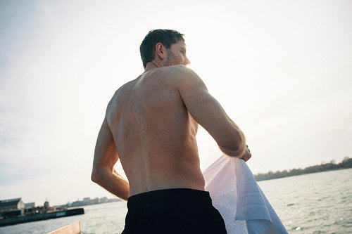 Man drying with towel by waterfront after cold dip in the ocean