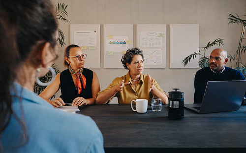 Group discussing project details during a board meeting in modern office.