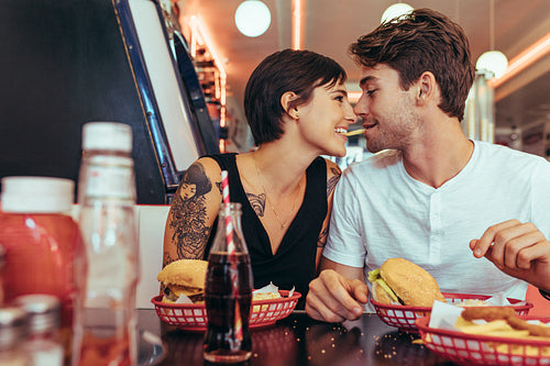 Coupe in romantic mood sharing a french fry at a restaurant