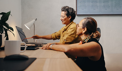 Two women collaborating on a project at an office desk