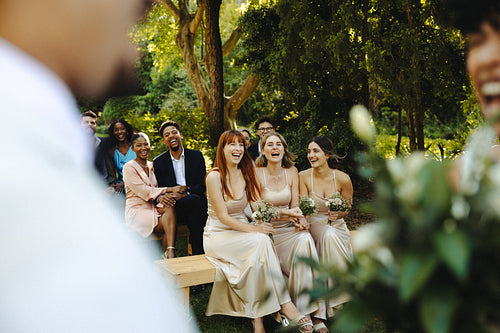 Laughing guests enjoying an outdoor wedding ceremony in a natural garden setting