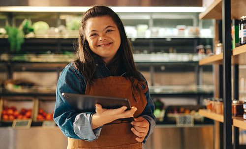 Happy store employee with Down syndrome standing in a supermarket