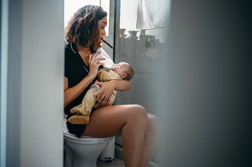 Mother feeds baby with bottle in bathroom