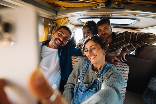 Friends take a group selfie inside a cozy van on a sunny road trip