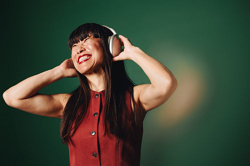 Mature woman wearing headphones listening to music in studio portrait