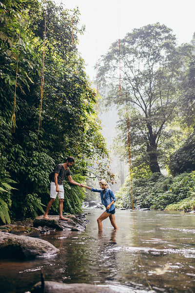 Man helping woman crossing stream
