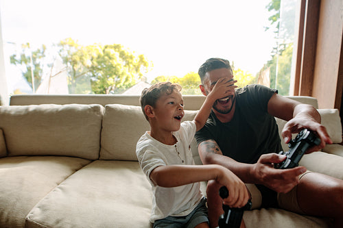 Cheerful father and son enjoying playing video game