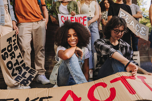 Happy teenage girl sitting with a group of youth peace activists