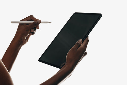 Person interacting with digital tablet using stylus pen on white background