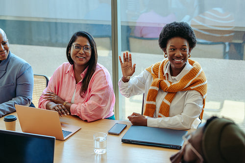 Creative agency meeting highlighting a person raising a hand to contribute innovative ideas