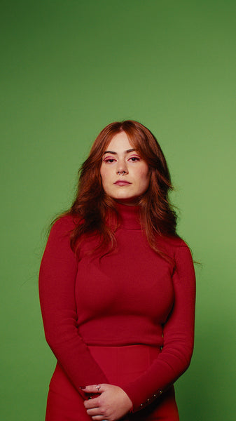 Confident model in red turtleneck poses on green screen for portrait shoot