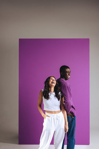 Vibrant couple laughing as they stand in a studio wearing stylish outfits
