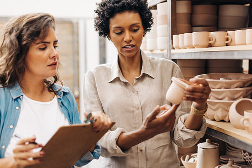 Female shop owners discussing one of their ceramic products