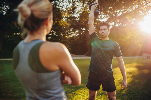 Fit man exercising with female trainer in park