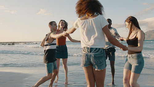 Friends playing ring around the rosy on the beach