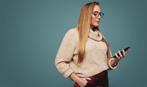 Self-assured woman using a mobile phone in a studio