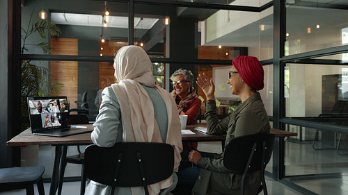 Collaborating through video conference: Female business team having an online meeting in a coworking office